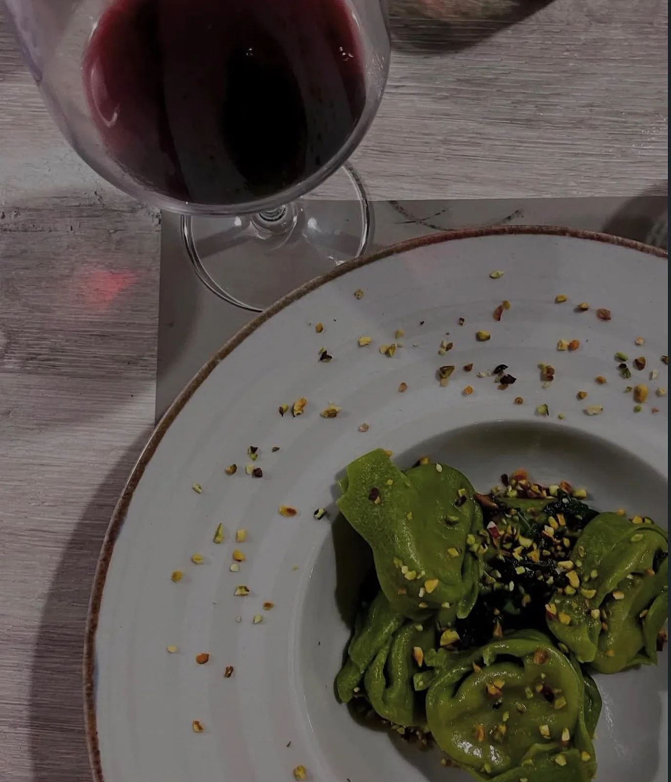 Balanzoni verdi con granella di pistacchio e un calice di rosso